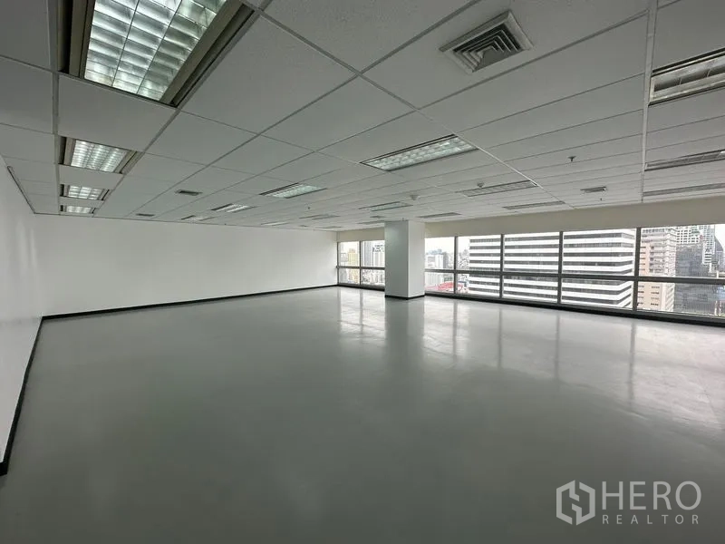 Office Space for rent - Bright office area with white walls, columns and wide city-view windows.