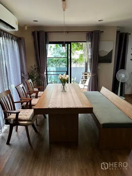 独立式住宅 出租在Prawet, Bangkok - 明亮餐区，木质餐桌与长凳，推拉门面向花园。