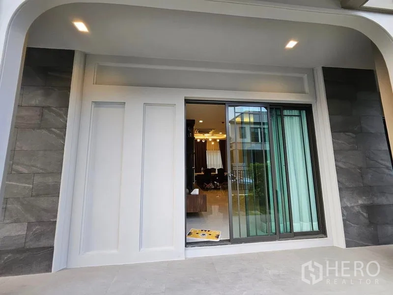 Detached House for sale in Mueang Pathum Thani, Pathum Thani - Covered patio with sliding glass doors opening to the living area.