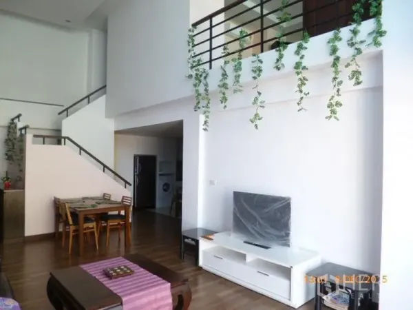 คอนโด ให้เช่าในPathum Wan, Bangkok - ห้องนั่งเล่นและรับประทานอาหารเพดานสูงโปร่งสว่าง มีชั้นวางทีวี บันไดขึ้นชั้นลอย และไม้เลื้อยตกแต่ง