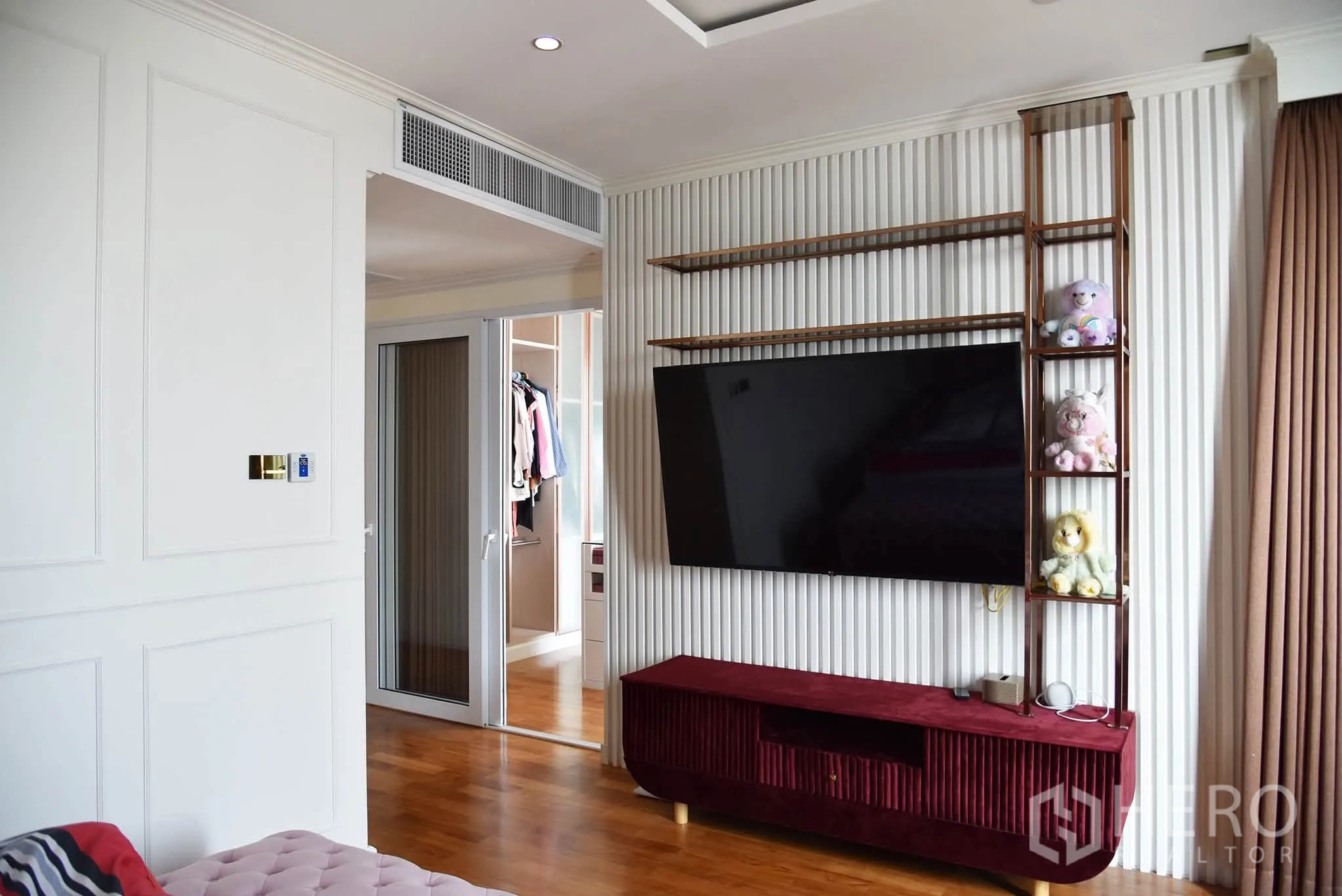 Condominium for sale in Khlong San, Bangkok - Bedroom area with wall-mounted TV, shelving, and doorway to a walk-in closet.