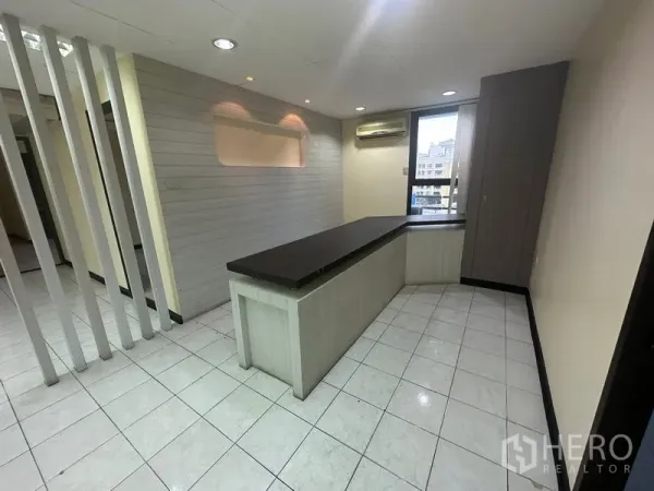 办公空间 出租在Bang Rak, Bangkok - 带内置接待台的区域，瓷砖地面、装饰墙和窗式空调。