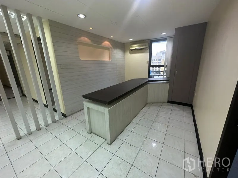 办公空间 出租在Bang Rak, Bangkok - 带内置接待台的区域，瓷砖地面、装饰墙和窗式空调。