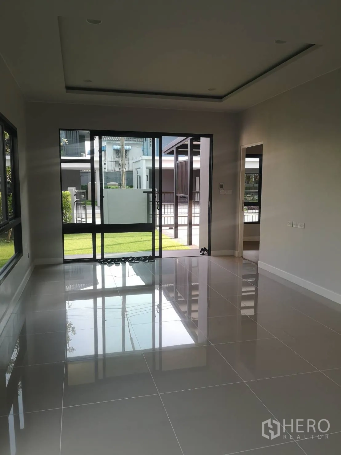 บ้าน ขายในLam Luk Ka, Pathum Thani - ห้องรับแขกชั้นล่าง พื้นกระเบื้องแกรนิตเงางาม ประตูกระจกเปิดสู่สนามหญ้า