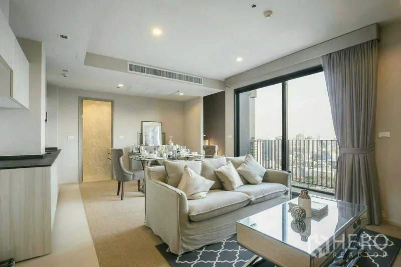 Condominium for rent or sale in Watthana, Bangkok - Stylish living area opening to a balcony with skyline views, adjacent to dining and kitchen.