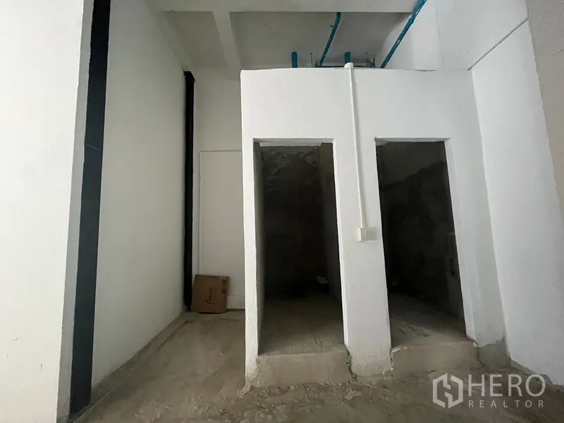 店屋 出租在Bang Rak, Bangkok - 两间未完工的卫生间隔间，顶部蓝色给水管