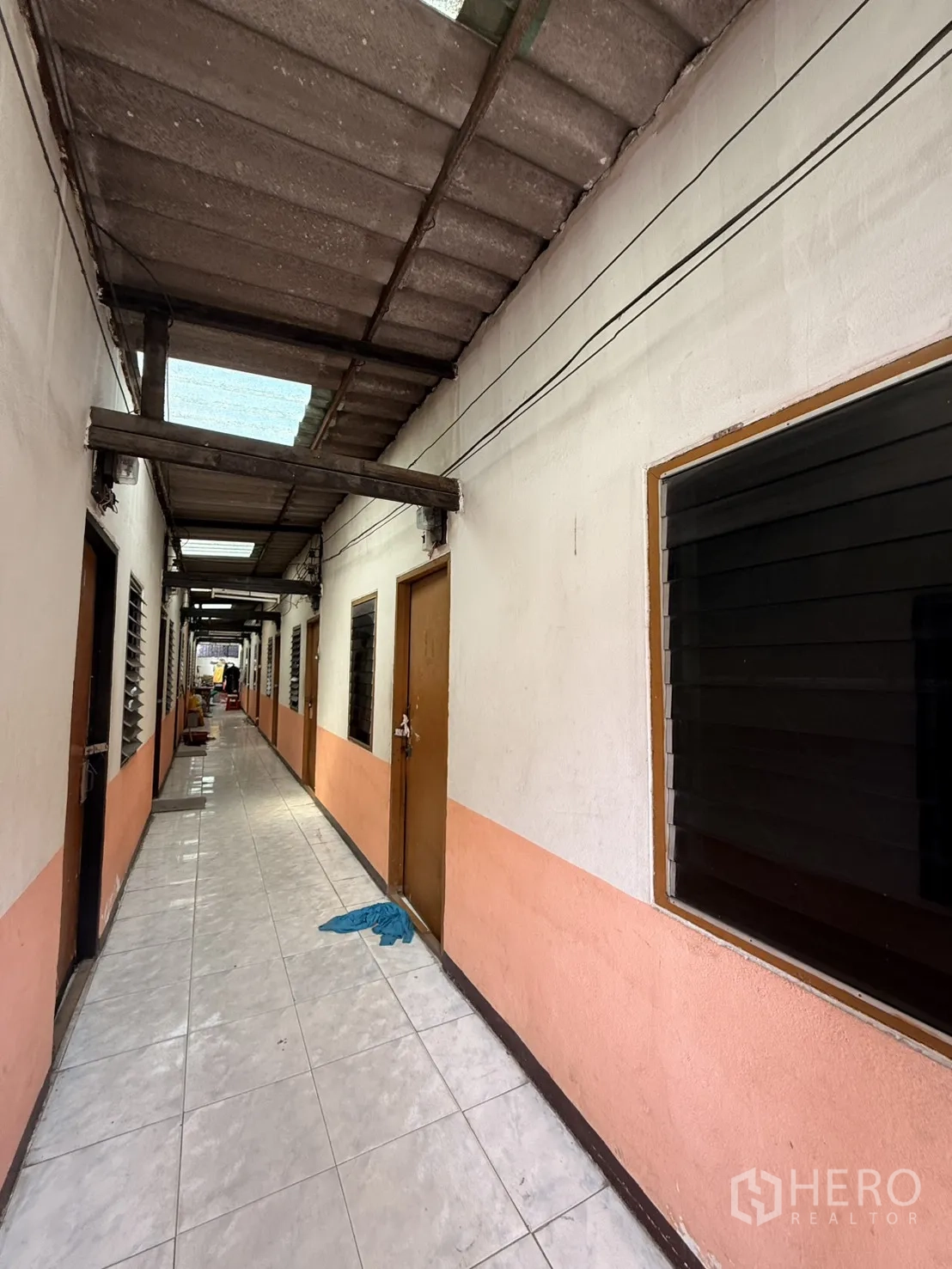 Warehouse for rent in Lam Luk Ka, Pathum Thani - Tiled corridor with multiple doors and windows inside the compound.