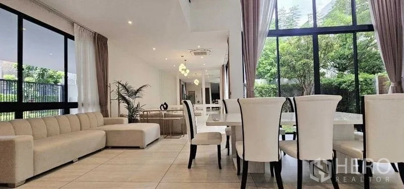 Detached House for rent in Bang Kapi, Bangkok - Open-plan living and dining area with tall windows and neutral furnishings.