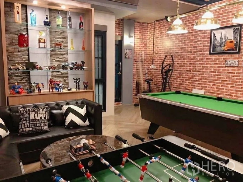บ้าน ขายในLam Luk Ka, Pathum Thani - ห้องเกมสไตล์ลอฟต์ ผนังก่ออิฐ โซฟาหนัง โต๊ะพูล โต๊ะฟุตบอล และชั้นโชว์ของสะสม.