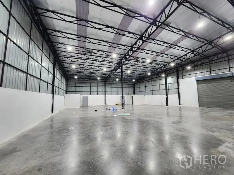 Warehouse for rent in Pak Kret, Nonthaburi - Spacious warehouse interior with polished concrete floor, high steel‑truss ceiling and LED lighting.