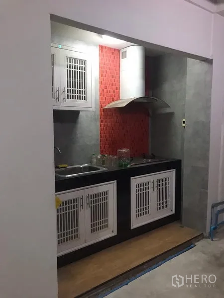 Detached House for rent in Din Daeng, Bangkok - Compact built-in kitchen with white cabinets, sink, cooktop, range hood and a red mosaic backsplash.