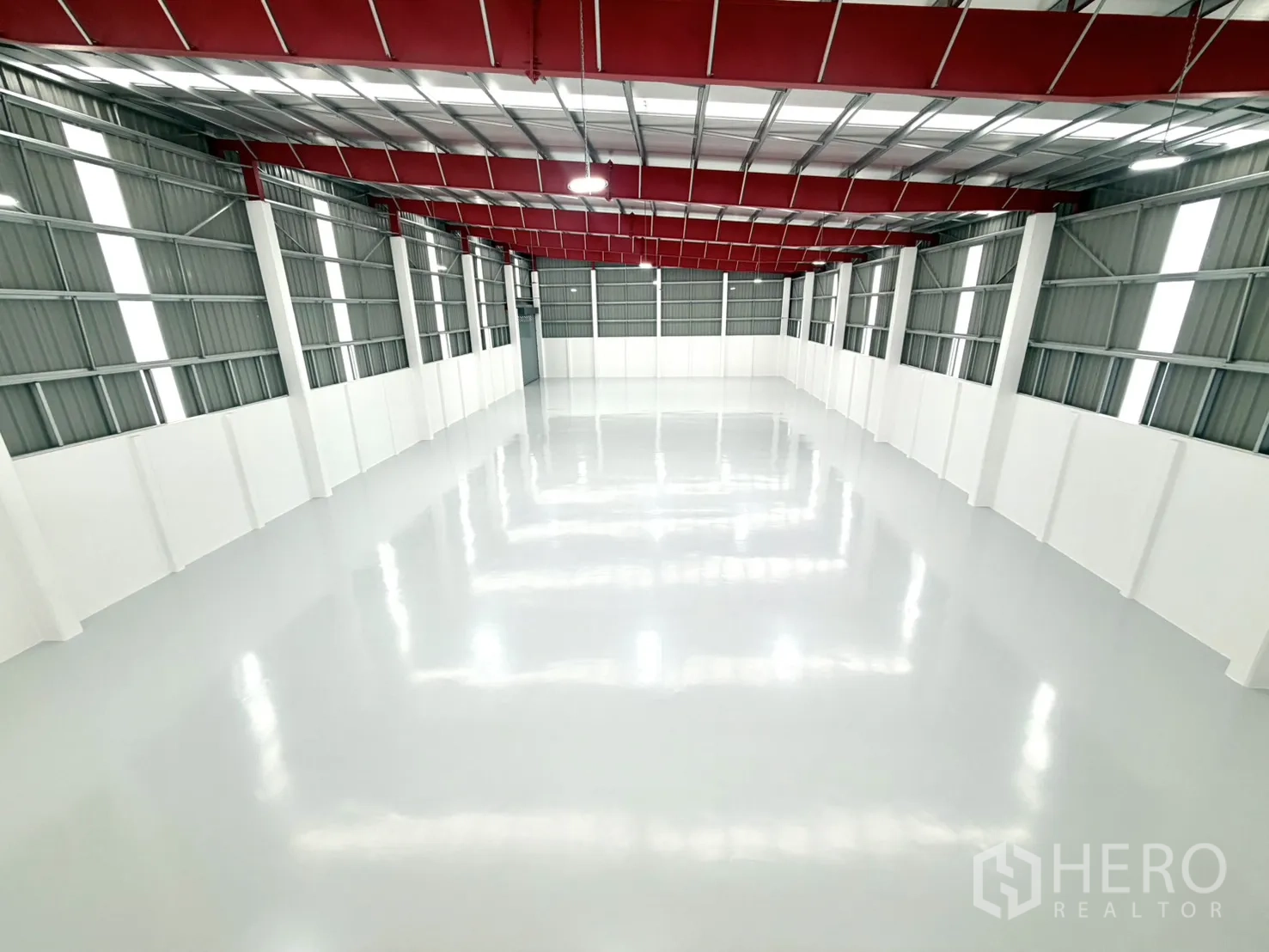 Factory for rent or sale in Lam Luk Ka, Pathum Thani - Elevated view of the clear-span factory floor with red steel beams.
