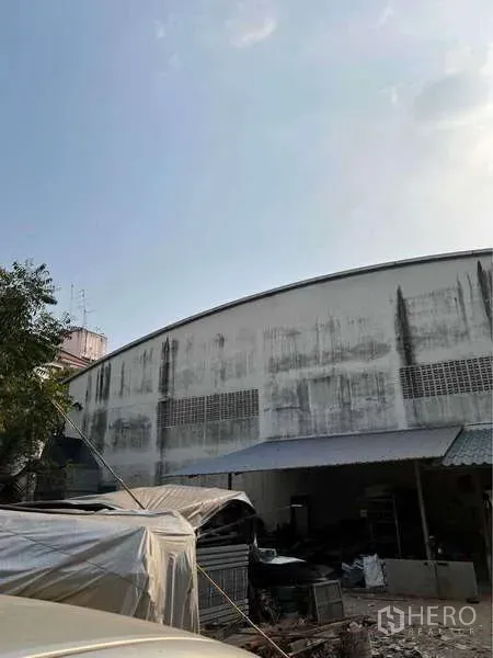 货栈 出售在Bang Bua Thong, Nonthaburi - 仓库后墙设通风砖与小型服务雨棚，旁边为储物区。