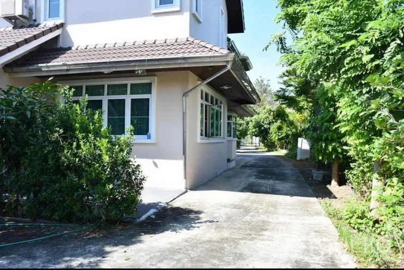 独立式住宅 出售在Sai Mai, Bangkok - 两层独栋别墅侧立面，长车道与茂密绿化。