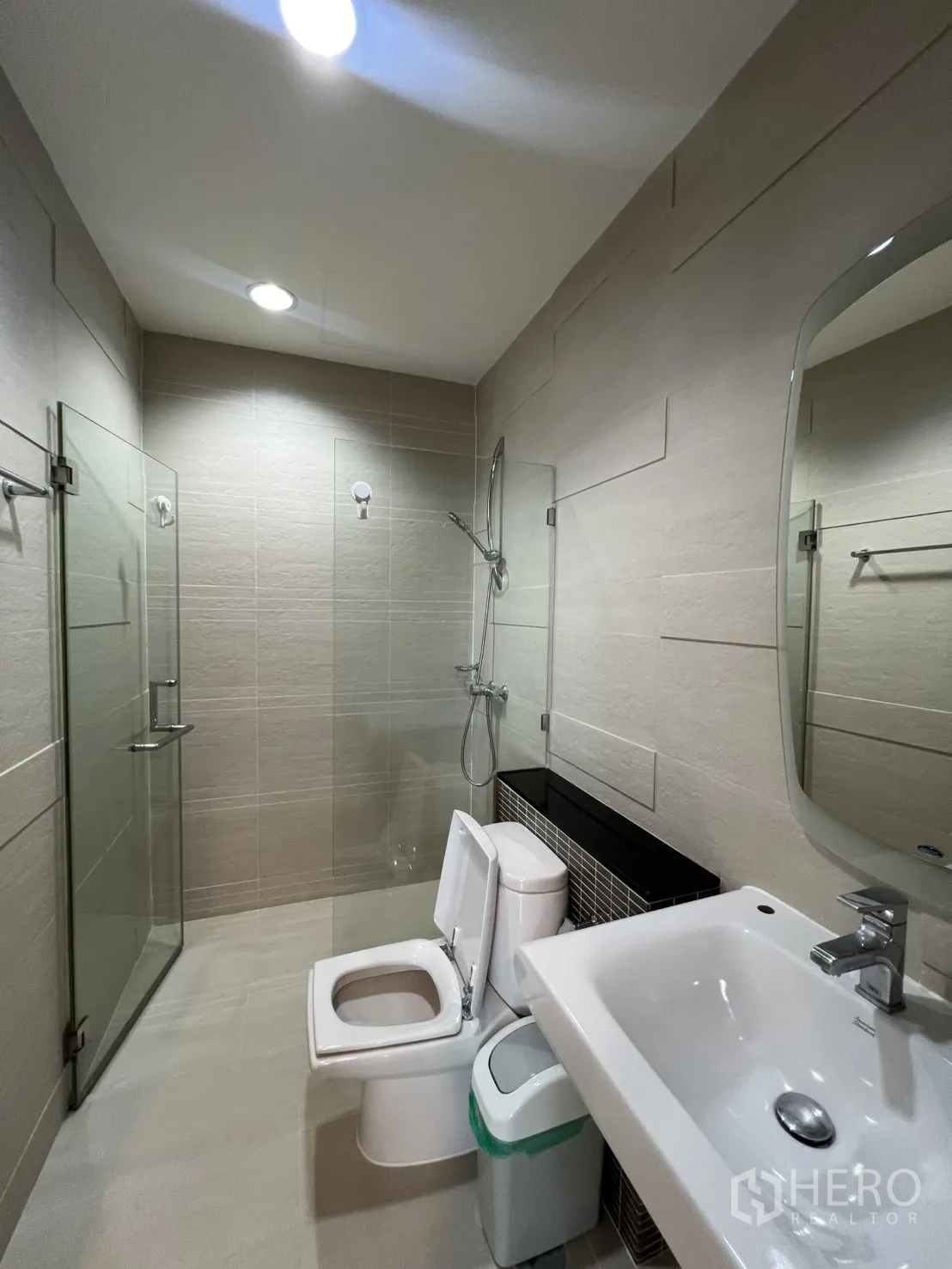 Condominium for rent in Bang Kapi, Bangkok - Contemporary bathroom featuring a glass-enclosed shower, toilet, and vanity.