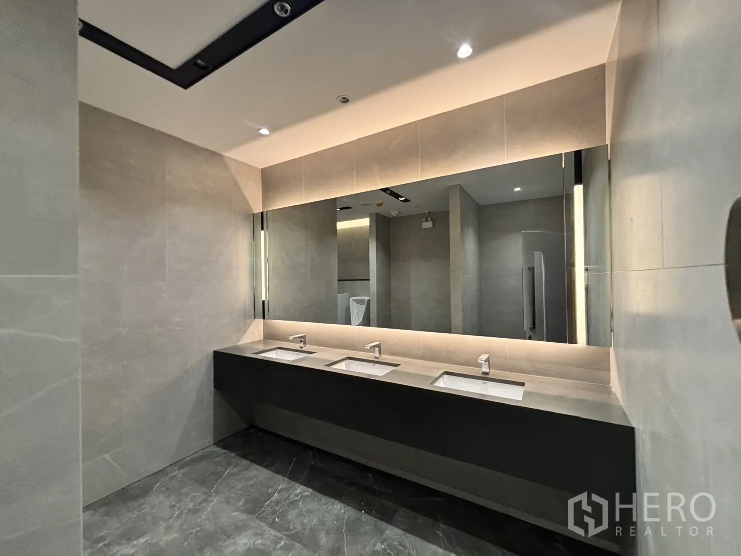 Office Space for rent in Huai Khwang, Bangkok - Modern office restroom with long vanity, three sinks and a backlit mirror.