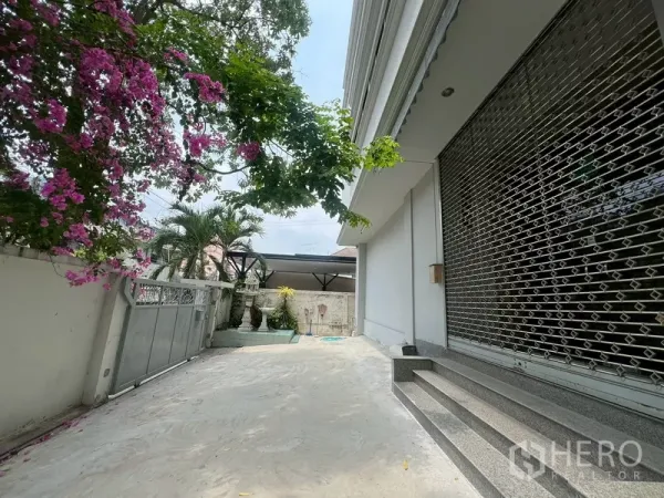 คลังสินค้า ให้เช่าในPhra Khanong, Bangkok - ทางรถเข้าร่มรื่นข้างอาคาร มีประตูรั้วและแปลงต้นไม้พร้อมประตูม้วนตะแกรง