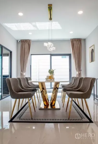 Detached House for rent in Bang Phli, Samut Prakan - Dining room with gold-base table, pendant light and sliding glass doors with curtains.