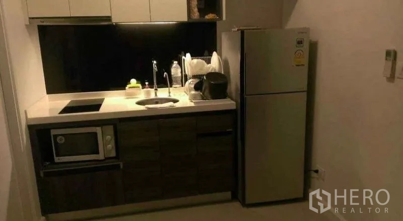 Townhouse for rent in Bang Phli, Samut Prakan - Compact modern kitchenette with cabinets, hob, sink, microwave and refrigerator.