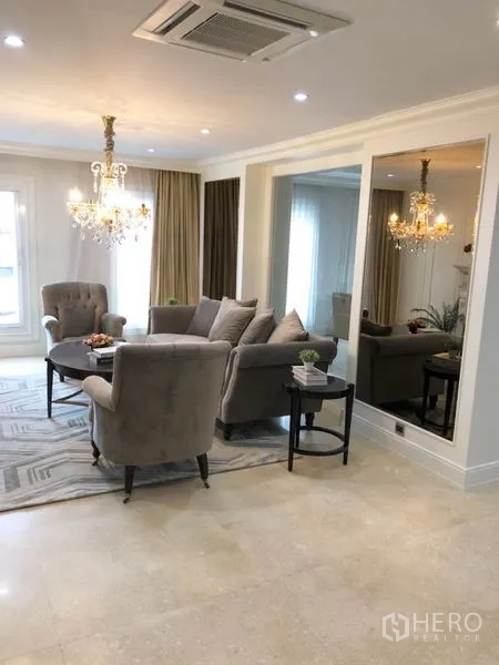 Shophouse for rent or sale in Chatuchak, Bangkok - Elegant sitting room with chandelier, large mirror and neutral sofa set.