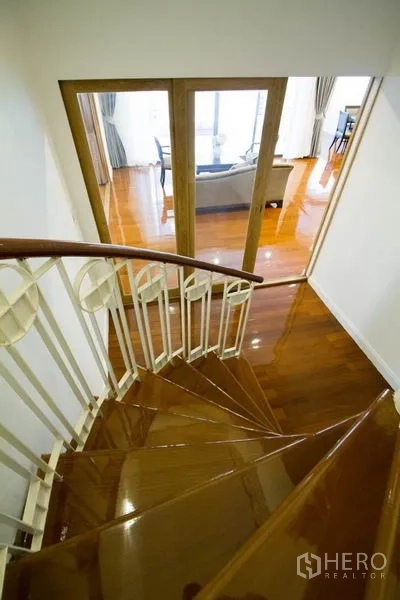 คอนโด ให้เช่าในWatthana, Bangkok - บันไดโค้งพื้นไม้ นำลงสู่ห้องนั่งเล่นที่สว่างด้วยประตูกระจก