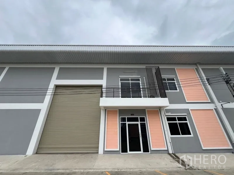 โรงงาน ให้เช่าในPhra Samut Chedi, Samut Prakan - ด้านหน้าโรงงานติดถนน ประตูม้วนสูง และประตูกระจกเข้าส่วนออฟฟิศ 2 ชั้น