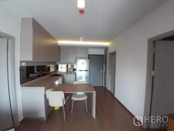 公寓 出租在Phra Khanong, Bangkok - 开放式厨房，配内置橱柜、长操作台、餐桌与冰箱的现代公寓。