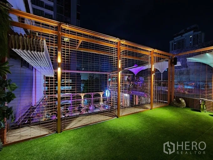 พื้นที่ขายปลีก ให้เช่า - ดาดฟ้าปูหญ้าเทียม โครงเหล็กตาข่าย และวิวเมืองยามค่ำคืน