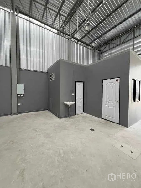Warehouse for rent in Phra Samut Chedi, Samut Prakan - Internal office and restroom block with sink and electrical panel inside the warehouse.