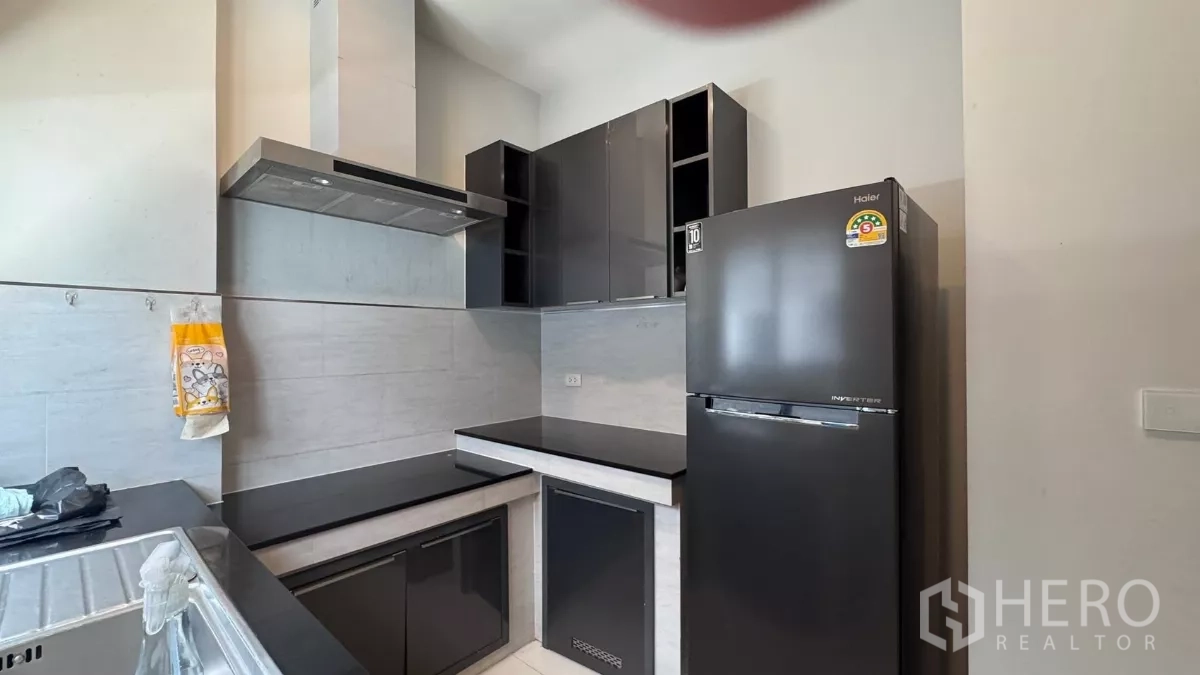 บ้าน ให้เช่าหรือขายในSaphan Sung, Bangkok - ครัวสมัยใหม่ขนาดกะทัดรัด ตู้เงาสีดำ เครื่องดูดควันสแตนเลส ตู้เย็น และผนังกระเบื้อง.