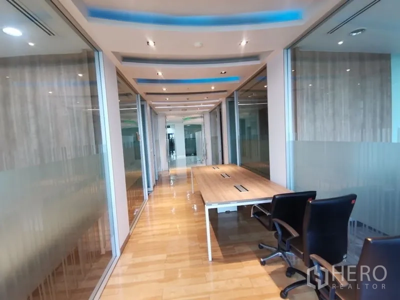 Office Space for rent in Bang Rak, Bangkok - Work corridor with shared bench desk, glass partitions and blue LED ceiling accents.