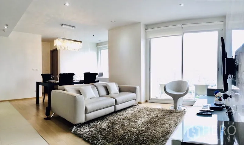 คอนโด ให้เช่าหรือขายในWatthana, Bangkok - ห้องนั่งเล่นคอนโดย่านทองหล่อ รับแสงธรรมชาติ โซฟาสีขาว พรมฟู และประตูกระจกสู่ระเบียง