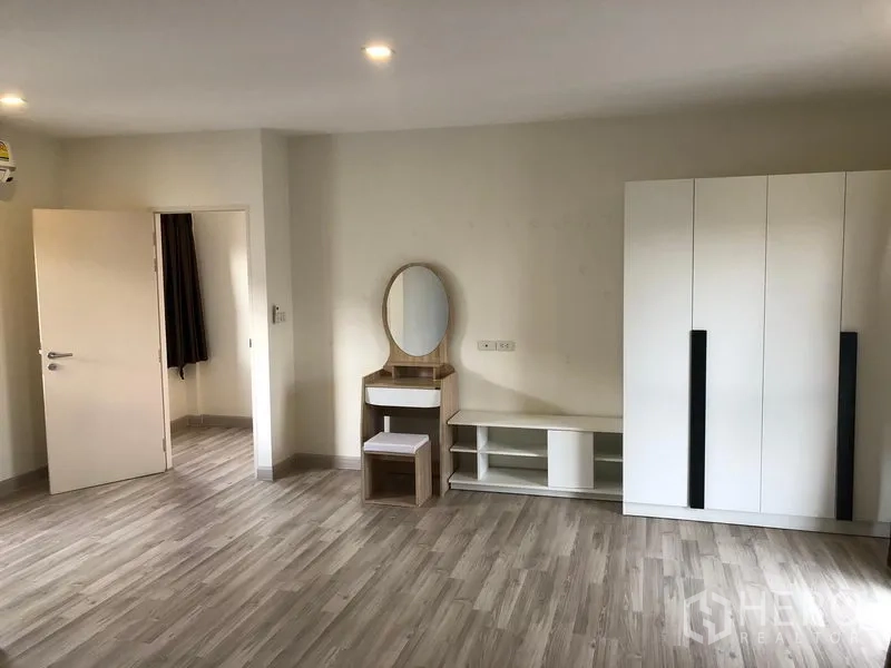 Townhouse for rent or sale in Saphan Sung, Bangkok - Dressing area featuring vanity table, wardrobe and TV console on wood floors.