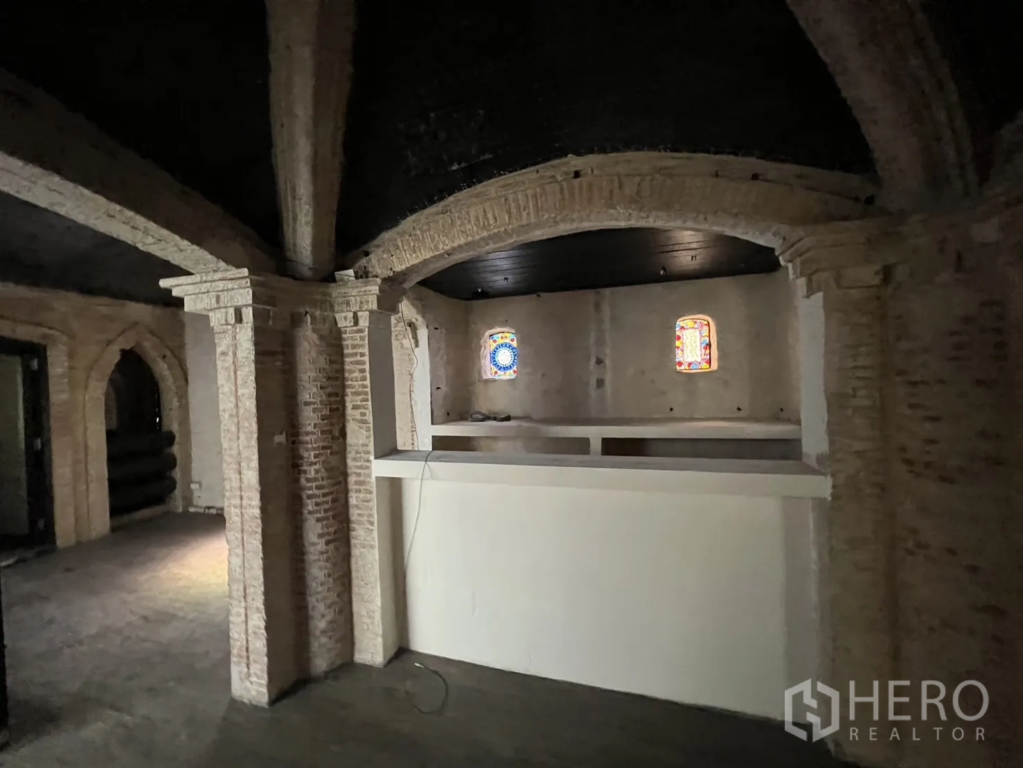 零售空间 出租在Watthana, Bangkok - 室内空间带砖拱与小彩窗，前方为服务台区域。