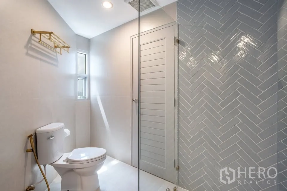 คอนโด ขายในBang Na, Bangkok - ห้องน้ำทันสมัย ฝักบัวกระจก ผนังกระเบื้องลายก้างปลา สีเทา และช่องแสงธรรมชาติ