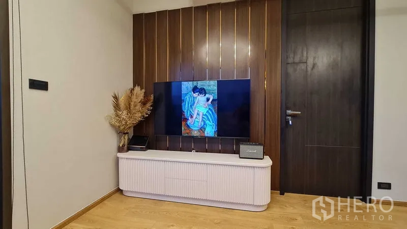 Condominium for rent in Watthana, Bangkok - TV wall with wood panel accent and a low media console in the living area.