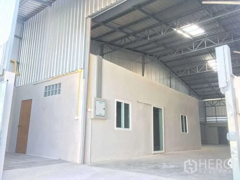 Warehouse for rent in Mueang Samut Prakan, Samut Prakan - Covered loading area with internal office block beneath a steel truss roof.