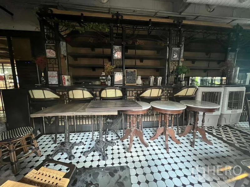 零售空间 出租在Watthana, Bangkok - 吧台区配高脚椅与小圆桌，花砖地面与背后置物架。