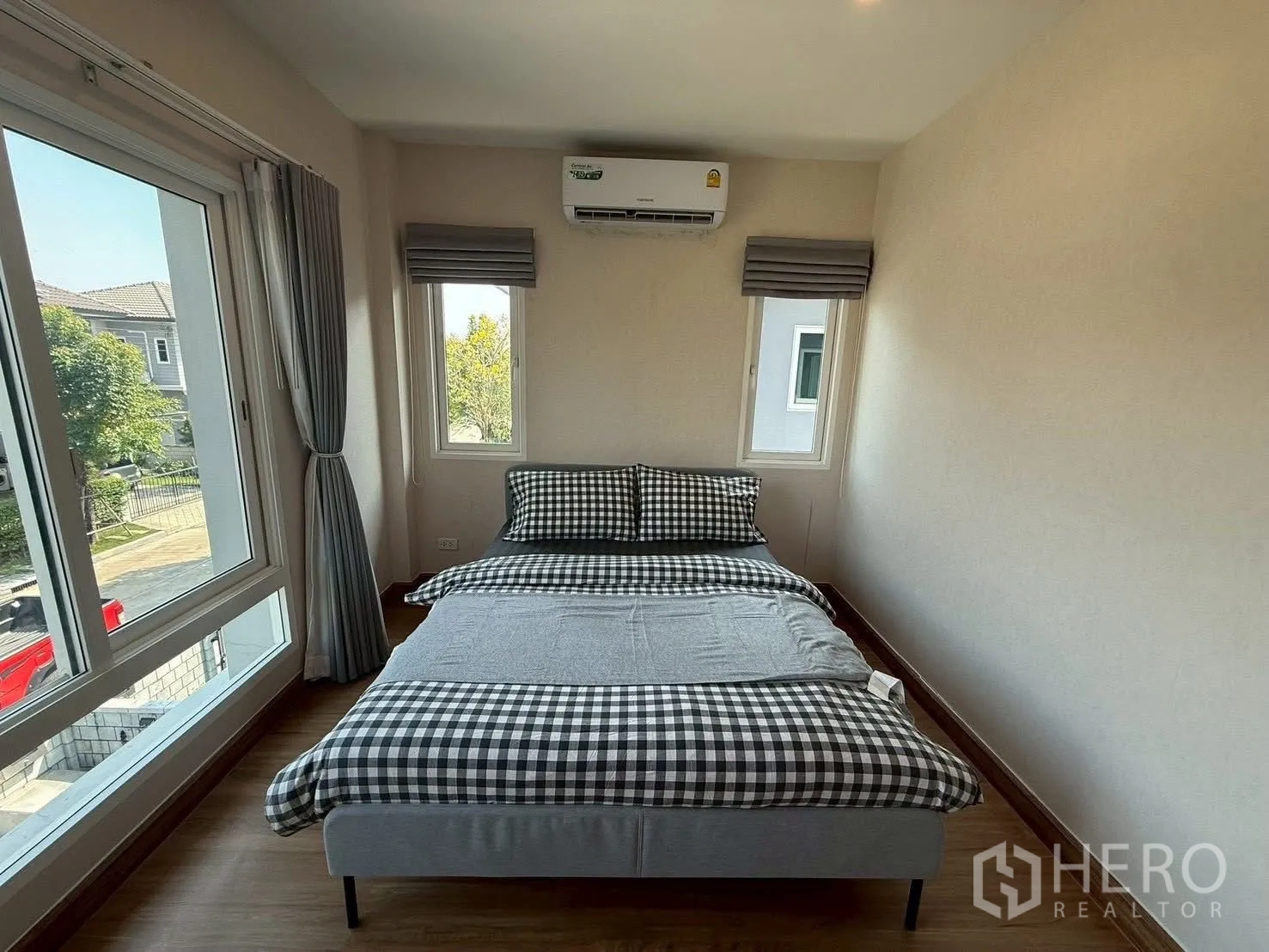 Detached House for rent in Prawet, Bangkok - Secondary bedroom with checkered duvet, air conditioner and corner windows.