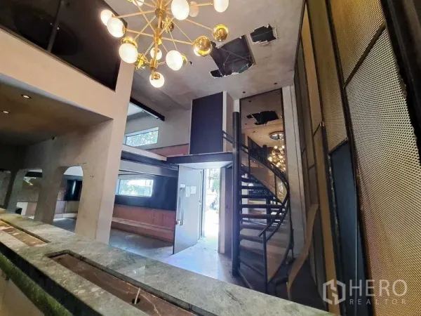 零售空间 出租在Watthana, Bangkok - 门厅开阔视角：金色吊灯、螺旋楼梯、夹层与拱形壁龛。