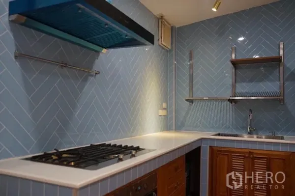 Detached House for rent in Wang Thonglang, Bangkok - U-shaped kitchen with blue herringbone tiles, gas hob, range hood and open shelves.