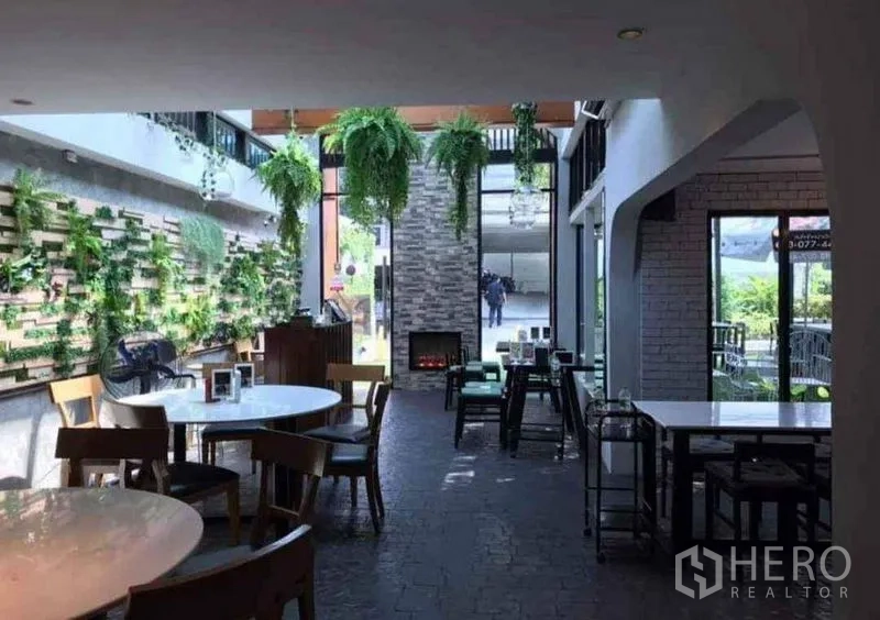 Retail Space for rent in Suan Luang, Bangkok - Bright retail interior with hanging greenery, a living green wall, stone feature fireplace, and large windows in Suan Luang.