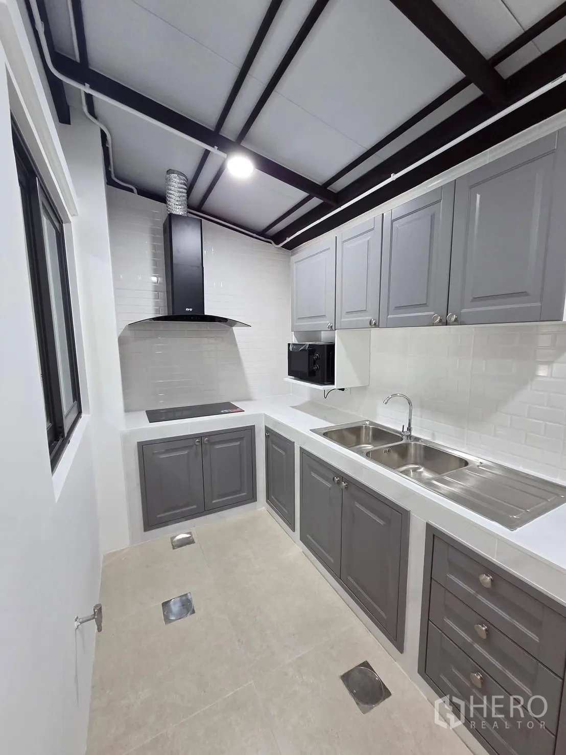 Townhouse for rent in Bang Phli, Samut Prakan - Separate kitchen with grey cabinets, double sink, induction cooktop, and range hood.