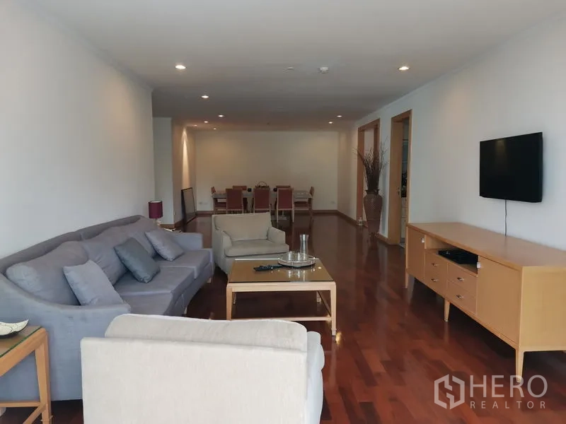 公寓 出租在Khlong Toei, Bangkok - 开放式客餐厅，配沙发、电视墙与亮丽木地板。