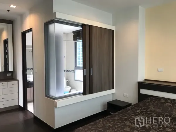Condominium for rent in Ratchathewi, Bangkok - Bedroom corridor with built-in wardrobe, dressing area and a glass partition looking into the ensuite bathroom.
