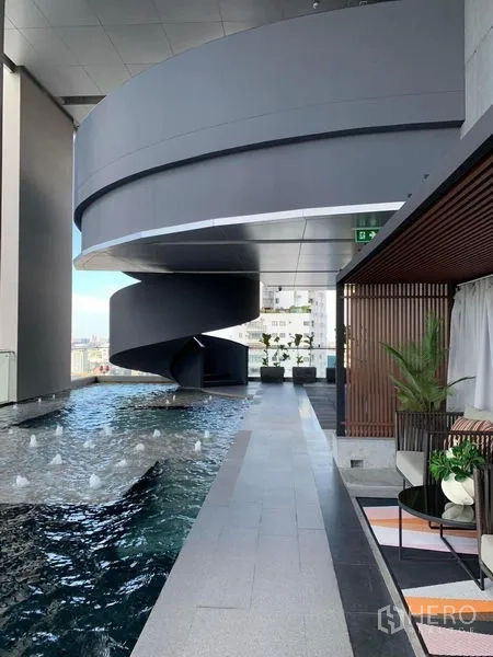 Condominium for rent in Watthana, Bangkok - Condominium facilities showing a lap pool, spiral walkway, and shaded lounge seating.