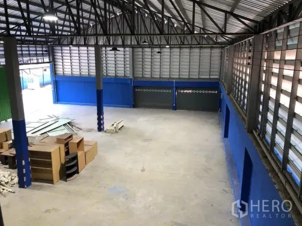 Warehouse for rent in Sai Mai, Bangkok - Spacious warehouse interior with roller shutters, steel columns and stacked boxes.
