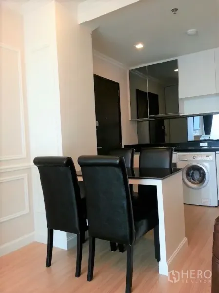 คอนโด ให้เช่าหรือขายในWatthana, Bangkok - มุมทานข้าวและครัวขนาดกะทัดรัด โต๊ะดำสี่ที่นั่ง ผนังกระจกเงา และเครื่องซักผ้าในห้อง