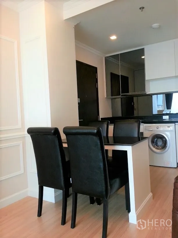 คอนโด ให้เช่าหรือขายในWatthana, Bangkok - มุมทานข้าวและครัวขนาดกะทัดรัด โต๊ะดำสี่ที่นั่ง ผนังกระจกเงา และเครื่องซักผ้าในห้อง