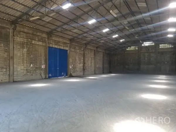 货栈 出租在Pak Kret, Nonthaburi - 大型仓库大厅，蓝色金属推拉门，通风砖墙设计。